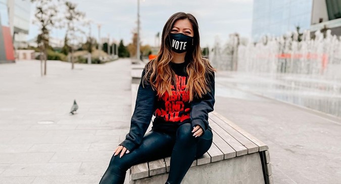 Une photo d'une femme portant un masque où il est écrit « Vote ».