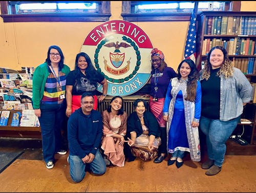 Des membres du personnel de Sapna et de NYC Votes posent ensemble devant un panneau indiquant « Entering the Bronx » (Entrer dans le Bronx)